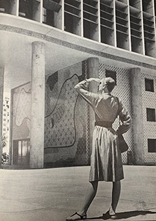 black and white photo of a woman looking at a building